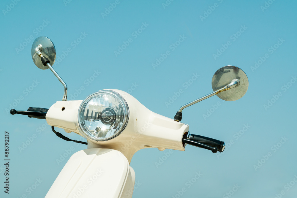 Fototapeta premium Detail of classic off-white scooter with headlight, handlebar and mirrors against blue sky