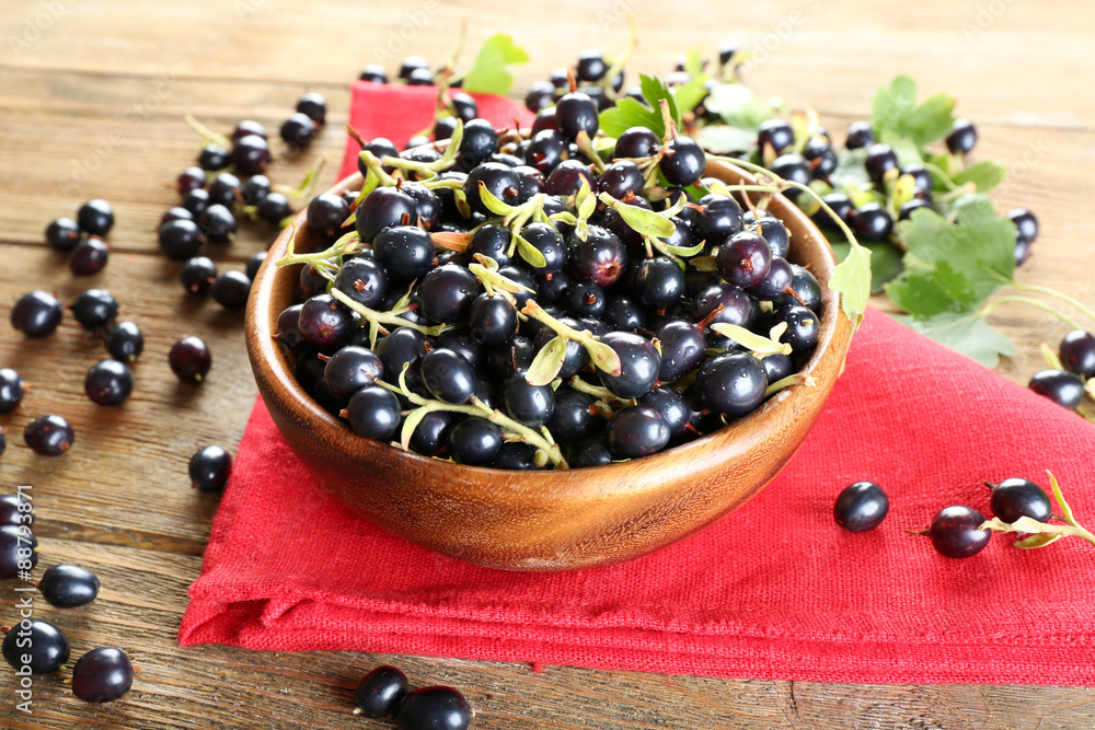 Ripe black currants in bowl on wooden table with red napkin, closeup Ripe black currants in bowl on wooden table with red napkin, closeup