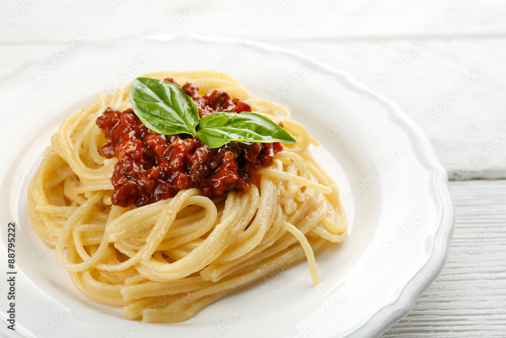 Spaghetti Bolognese on white plate, on color wooden background