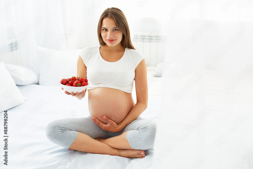 Pregnant Woman Eating Strawberry at home. Healthy Food Concept.