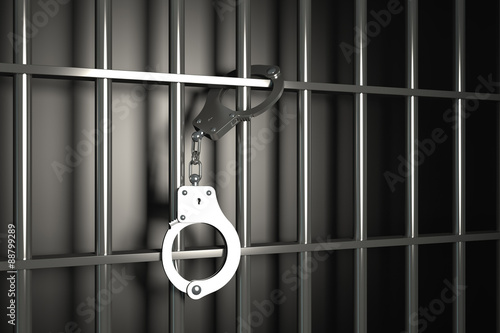 Fotografija metal prison bars with handcuffs on black background