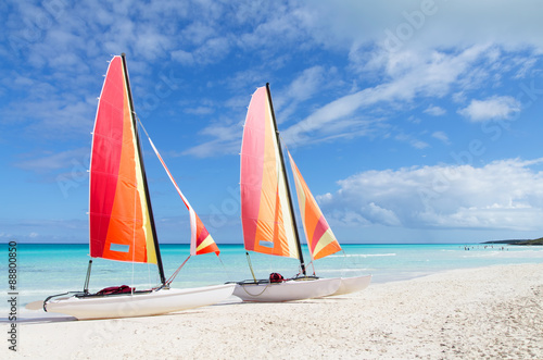 Two catamarans with its colorful sails wide open on Cuban white
