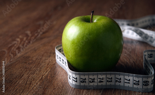 fresh green apple on a wooden table with measure