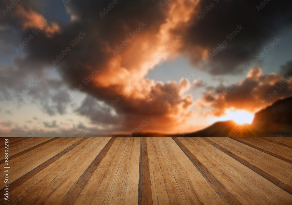 Sunrise and mountains refelcted in sea with wooden planks floor