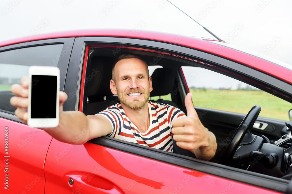 Man in car showing smart phone.