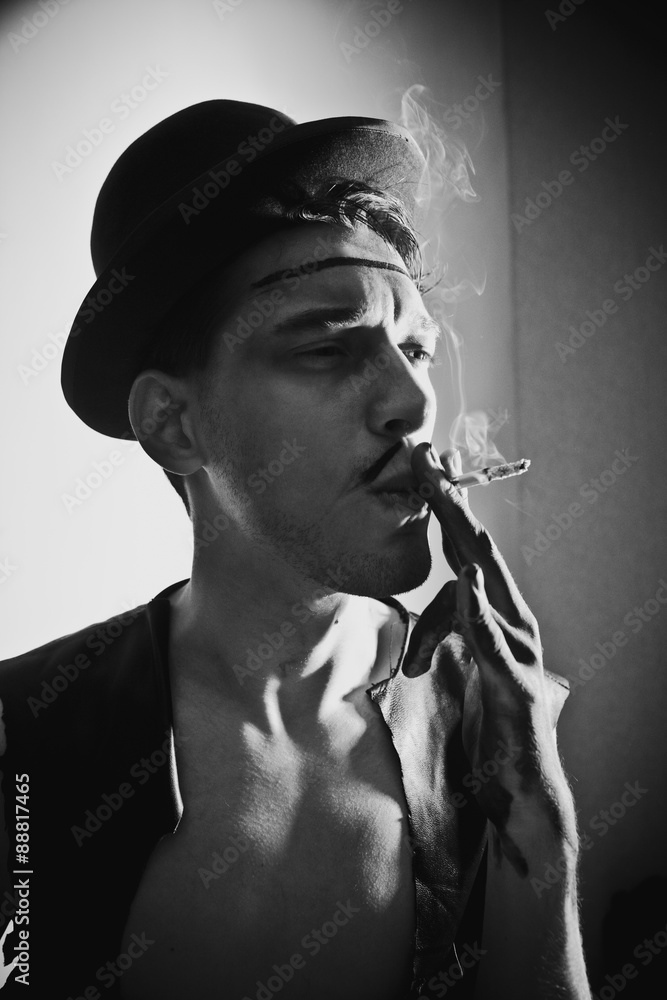 Retro portrait of beautiful young man in a hat with a cigarette Retro portrait of beautiful young man in a hat with a cigarette