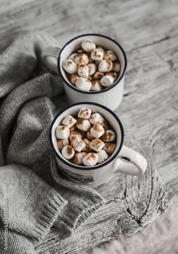 hot chocolate with marshmallows in ceramic mugs on a light wooden surface