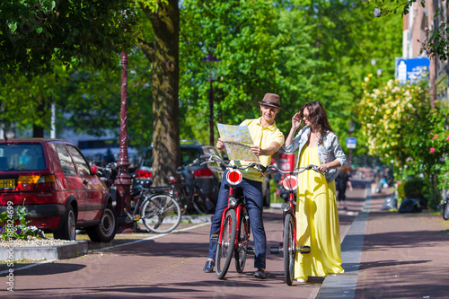 Young happy couple with city map on bikes in Amsterdam