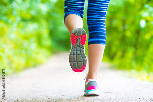 Closeup on shoe of athlete runner woman feet running on road 