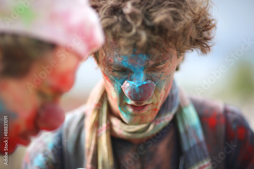 Painted face of a clown looking down, holi festival