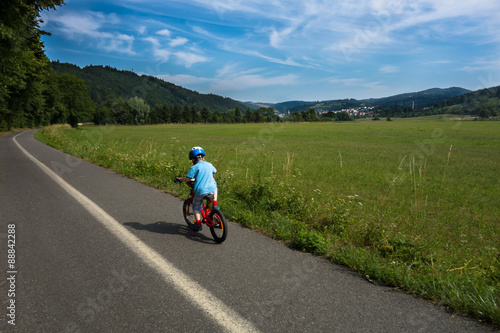 child riding alone first bike on cycling way outside the city