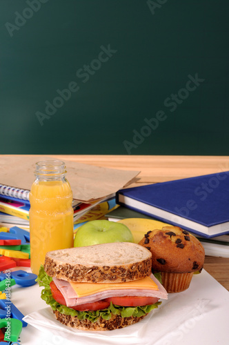 Packed school lunch on classroom desk with blackboard, copy space, vertical