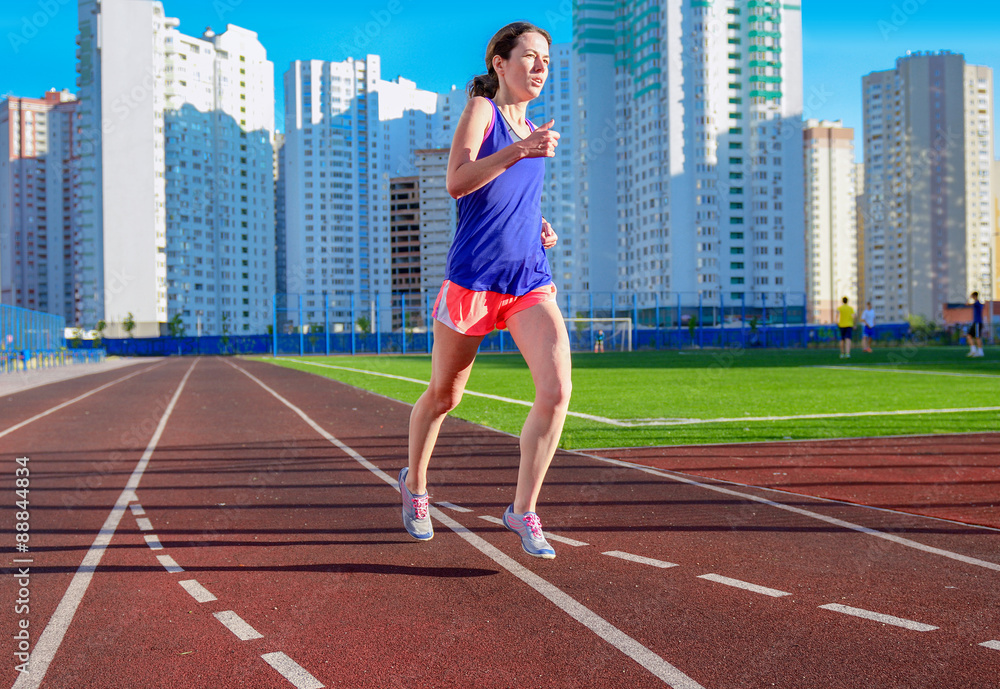Woman jogging on track, running and working out on stadium, sport in megapolis

