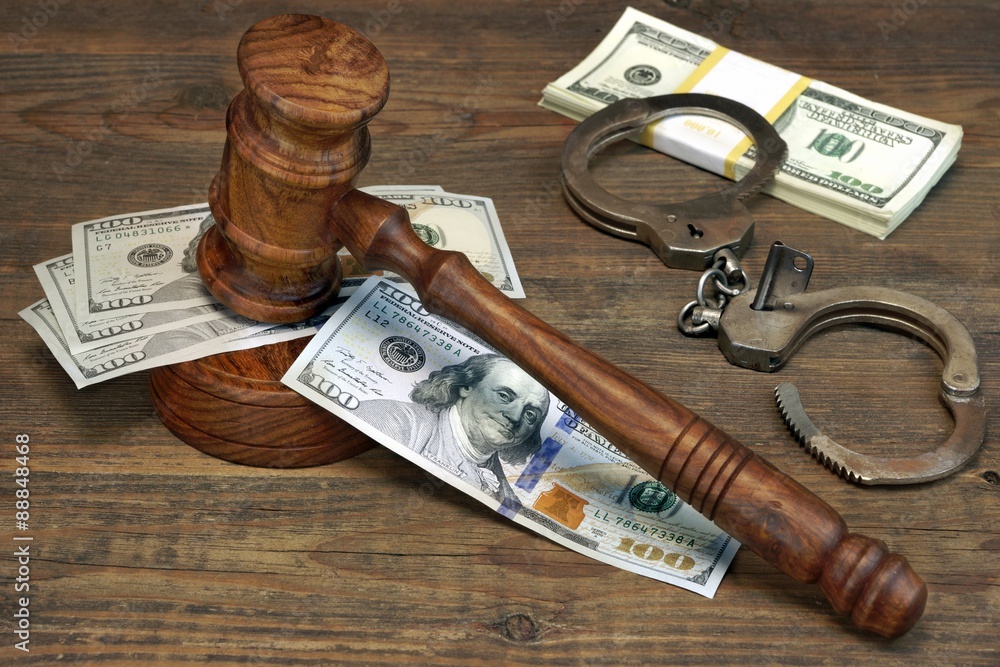 Dollar Cash, handcuffs and judge gavel on wood table