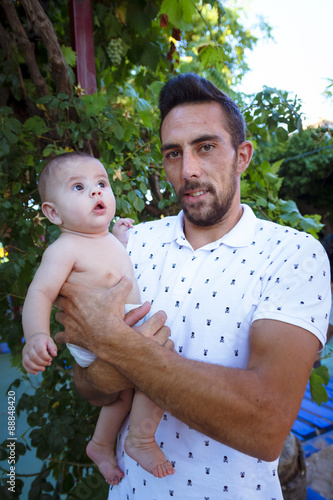 Bebe en brazos de su padre jugando en el parque. Primer plano de un padre jugando con su bebe desnudo en pañal. Bebe feliz. photo