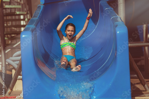 Child sliding down water slide in pool