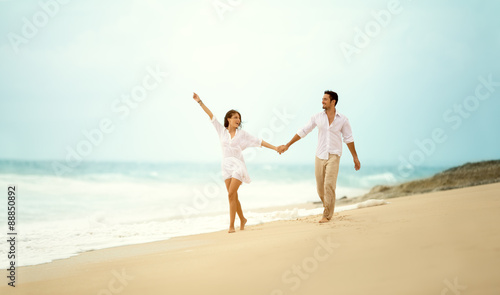 laughing couple in love holding hand on beach