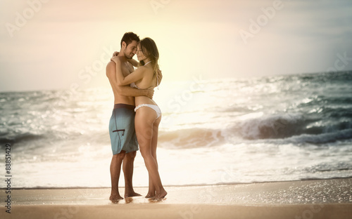 Young beautiful couple in love on the beach on sunset