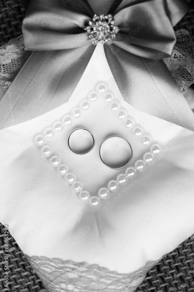 Obraz premium Gold wedding rings on a pillow.