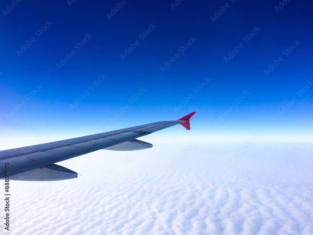 Fototapeta premium Wing of the plane with cloudy sky on background