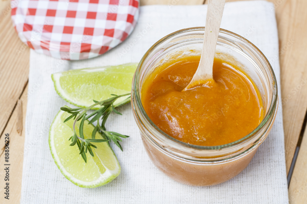 Homemade apricot jam and fresh apricots, lime and rosemary with leaves on the wooden table Homemade apricot jam and fresh apricots, lime and rosemary with leaves on the wooden table
