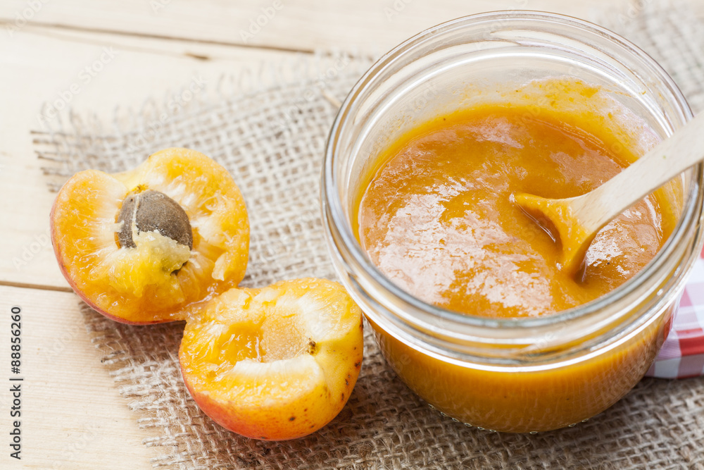 Homemade apricot jam and fresh apricots with leaves on the wooden table Homemade apricot jam and fresh apricots with leaves on the wooden table