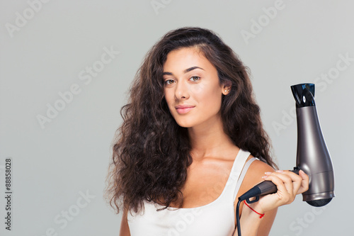 Cute attractive woman holding hairdrye