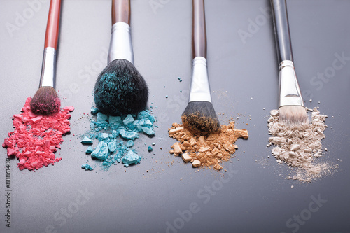 Makeup brushes on background with colorful powder.
