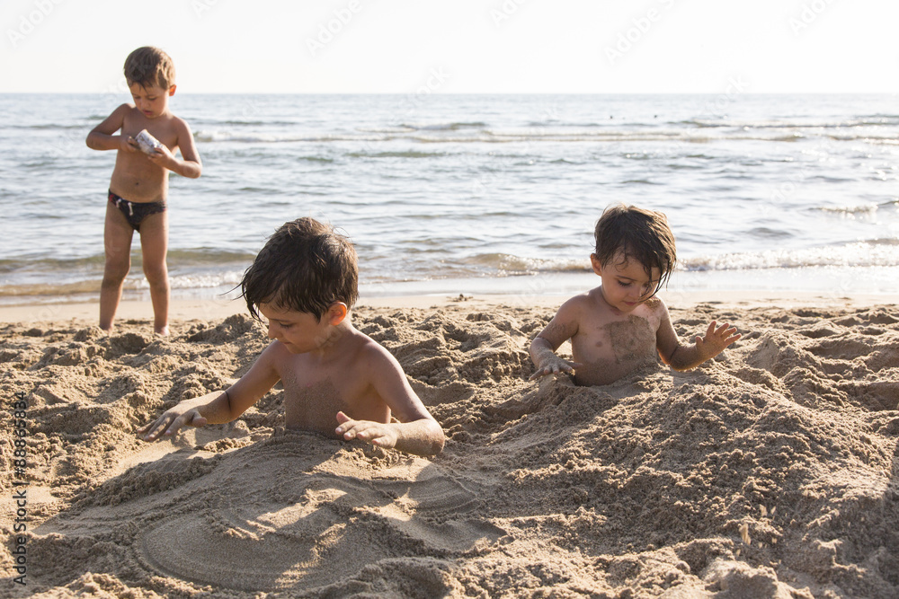 Tre bambini che giocano con la sabbia in riva al mare Stock Photo | Adobe  Stock