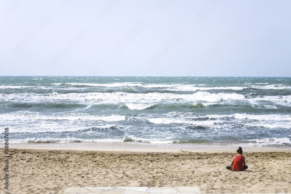 Girl seats on the beach during a storm Girl seats on the beach during a storm