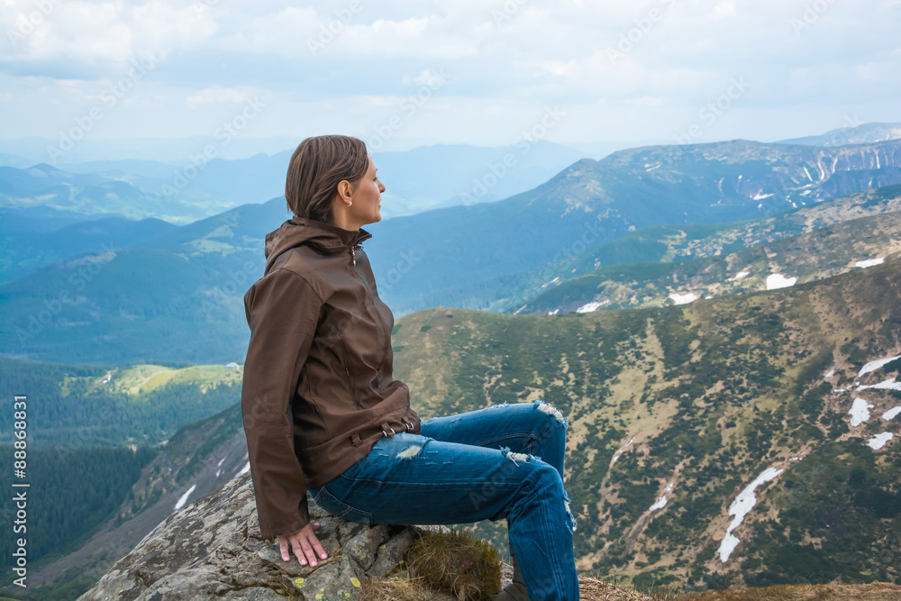 Naklejka premium Girl is sitting on a mountain top