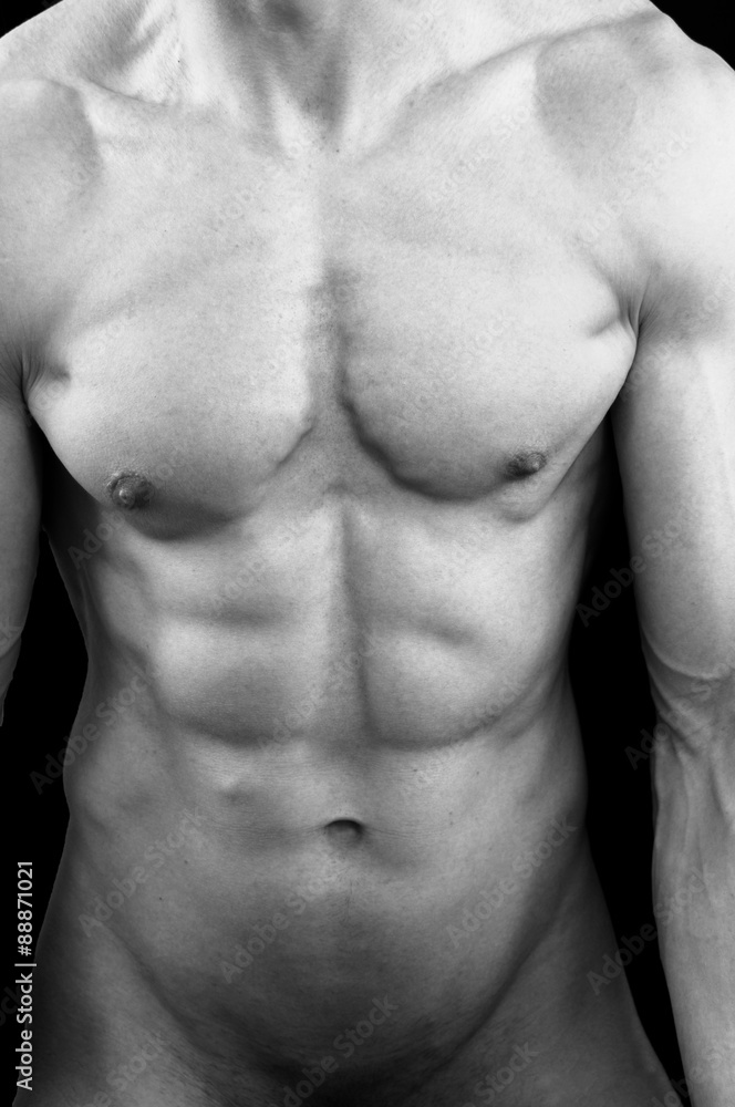 The torso of a lean but muscular young man. In black and white. Black studio background. The torso of a lean but muscular young man. In black and white. Black studio background.