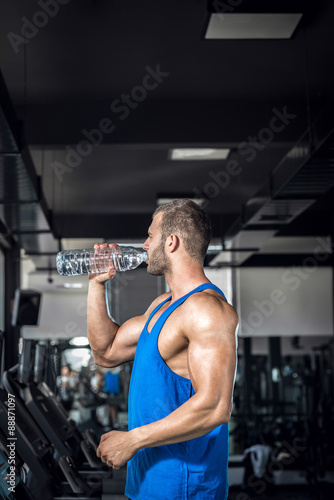 Fototapeta Naklejka Na Ścianę i Meble -  Young man drinking water in gym