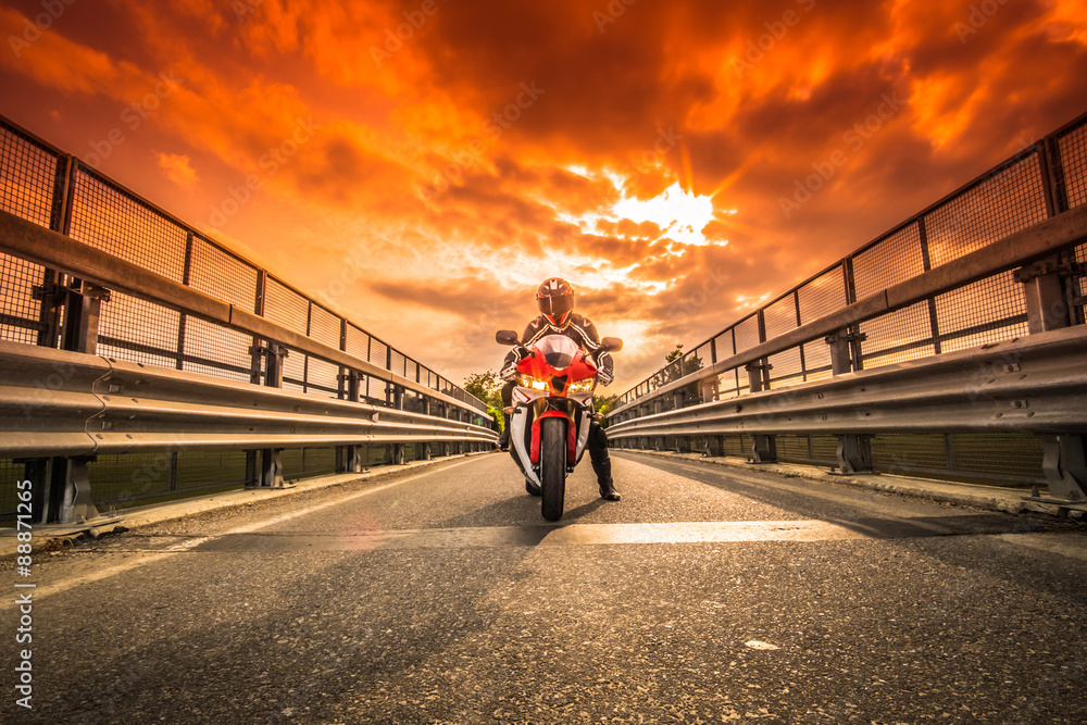 Moto da strada pronta alla partenza sotto un cielo rosso al tramonto  Stock-Foto | Adobe Stock