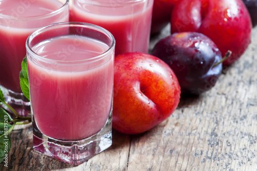 Delicious fresh juice of red and blue sweet plums and peach in a