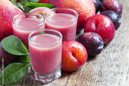 Delicious fresh juice of red and blue sweet plums and peach in a