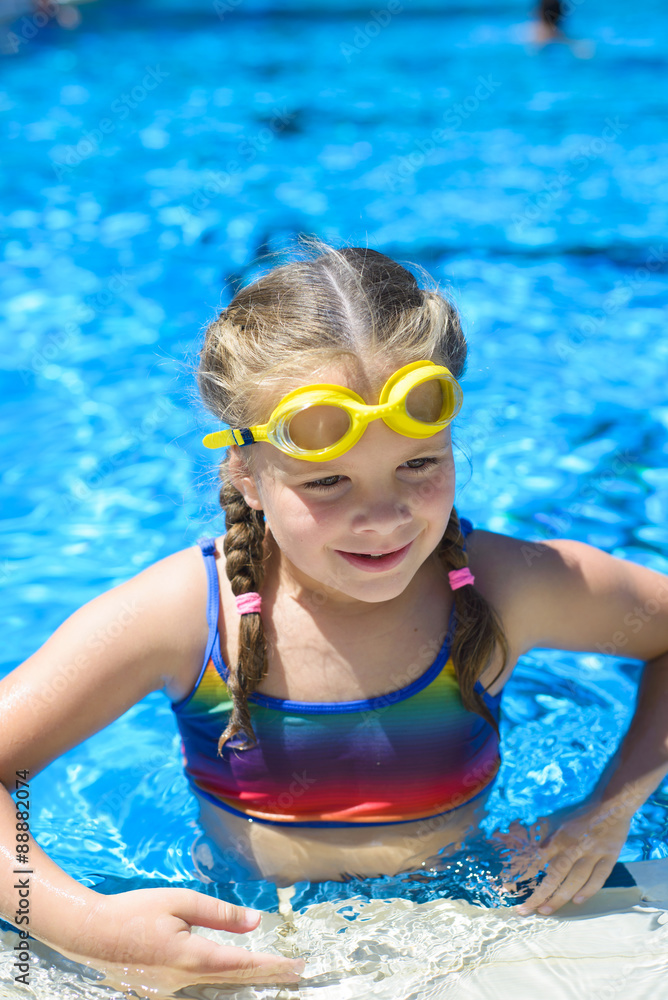 Smiling little girl in swimming goggles in the swimming pool