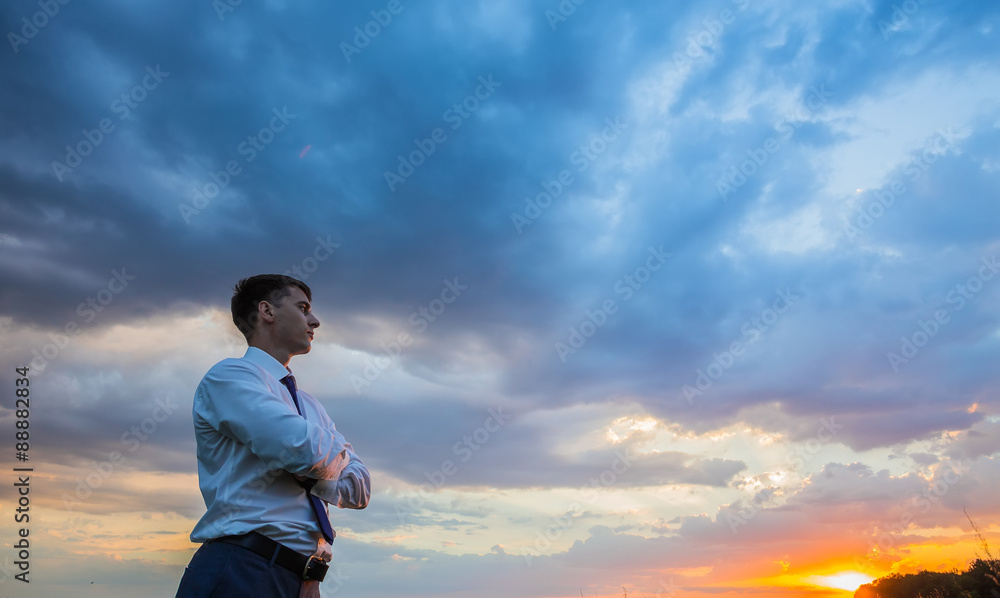 businessman standing on field to face the sunset