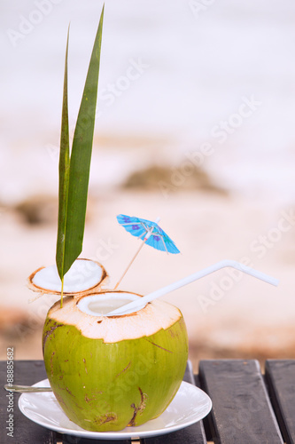 Coconut water drink served in coconut with drinking straw on the table