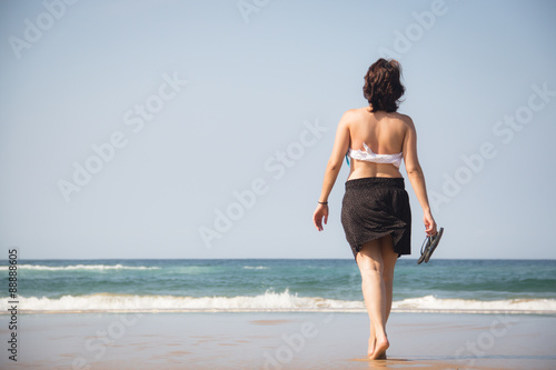 Girl walking towards the sea with flip flops in her hands on the beach in Ponta Do Ouro in Mozambique 