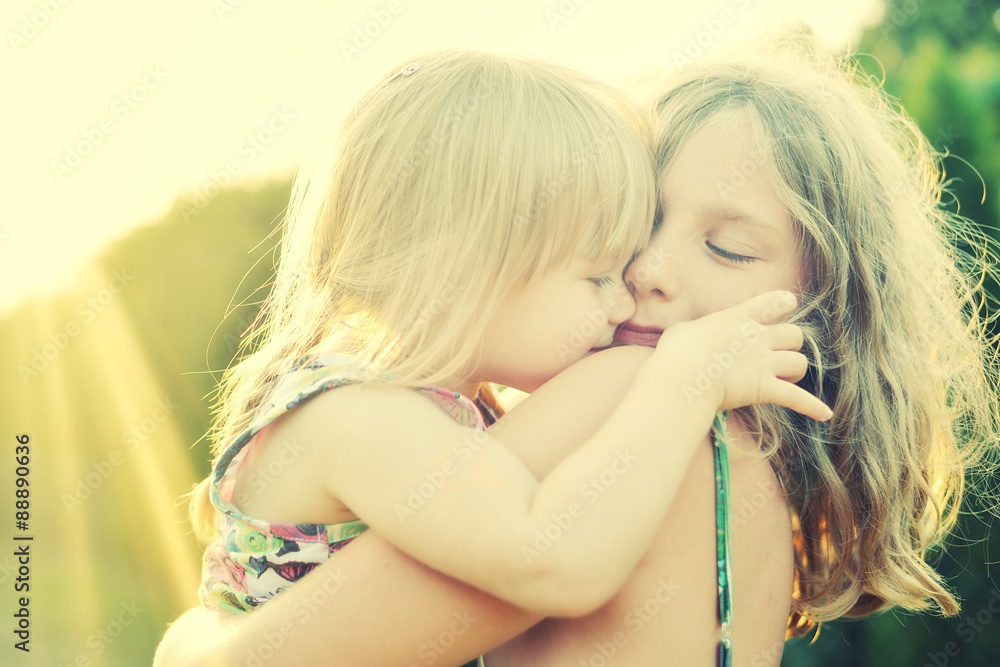 Two sisters Cuddled up together. Back lighting sunlight.