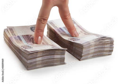 Two fingers of a hand at the stacks of Russian paper money