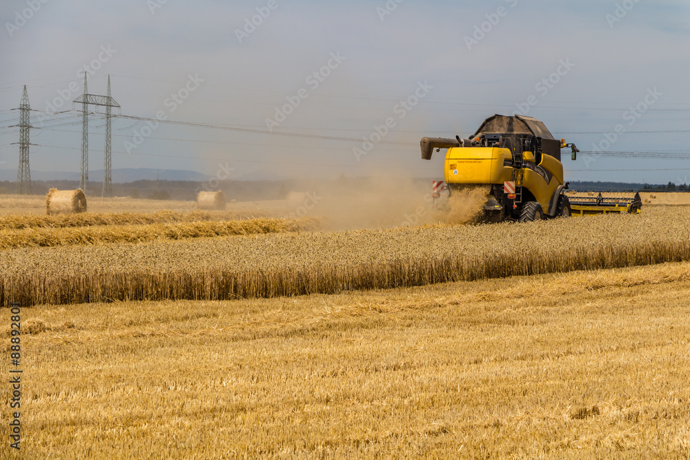 Fototapeta premium yellow combine harvester working in wheat field 