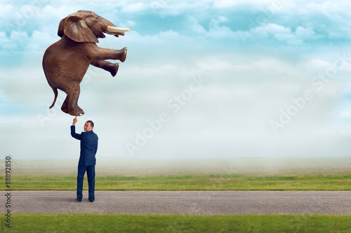 businessman holding an elephant with one finger photo