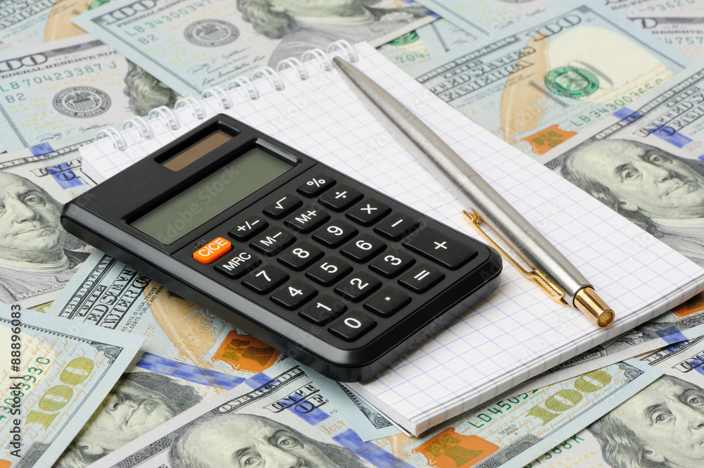 Calculator, pen and notepad on dollars Calculator, pen and notepad on dollars