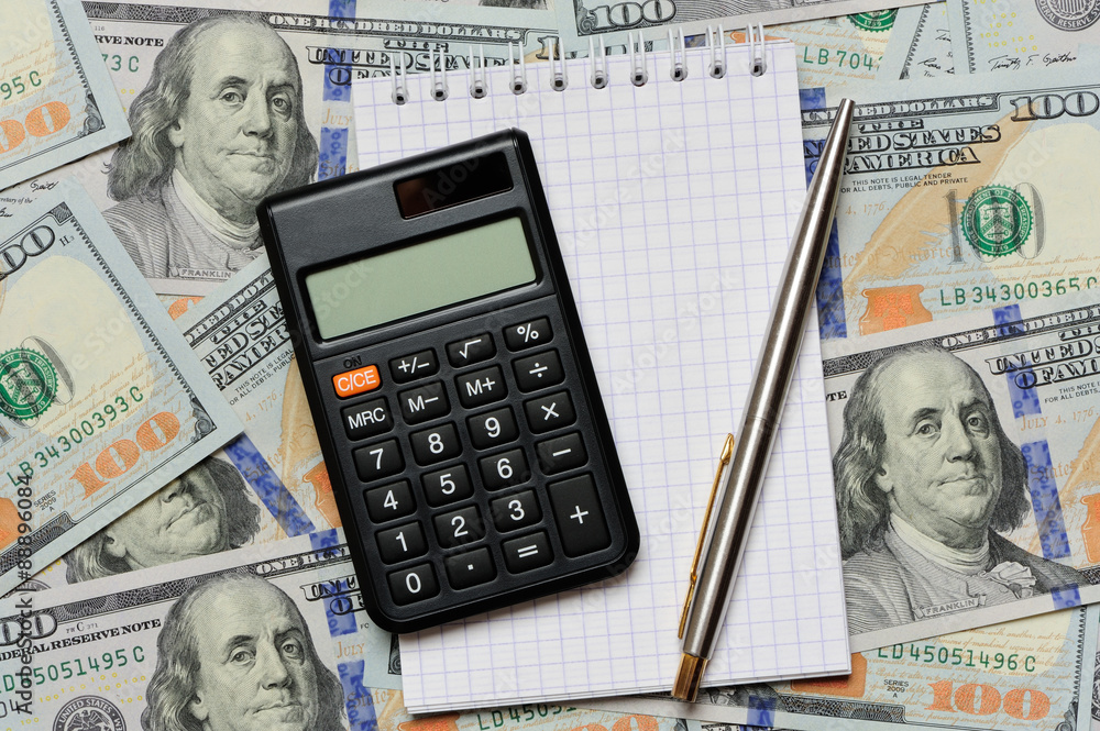 Calculator, pen and notepad on dollars Calculator, pen and notepad on dollars