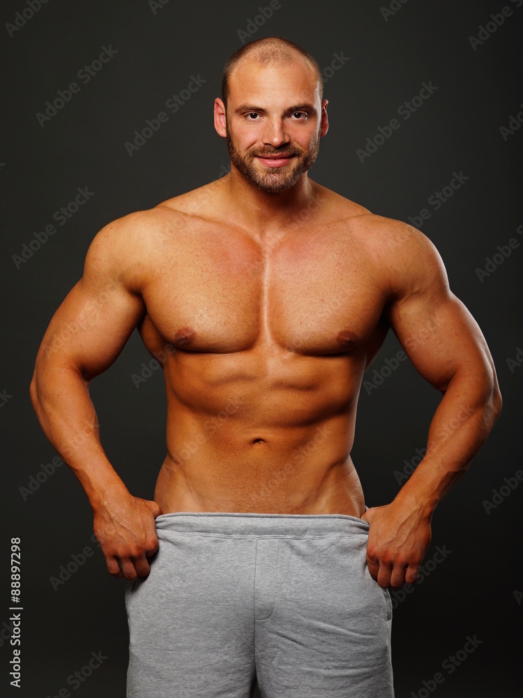 Fototapeta premium Muscular man standing and poses on gray background