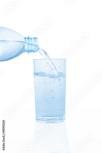 Pouring water on a glass on white background. This has clipping