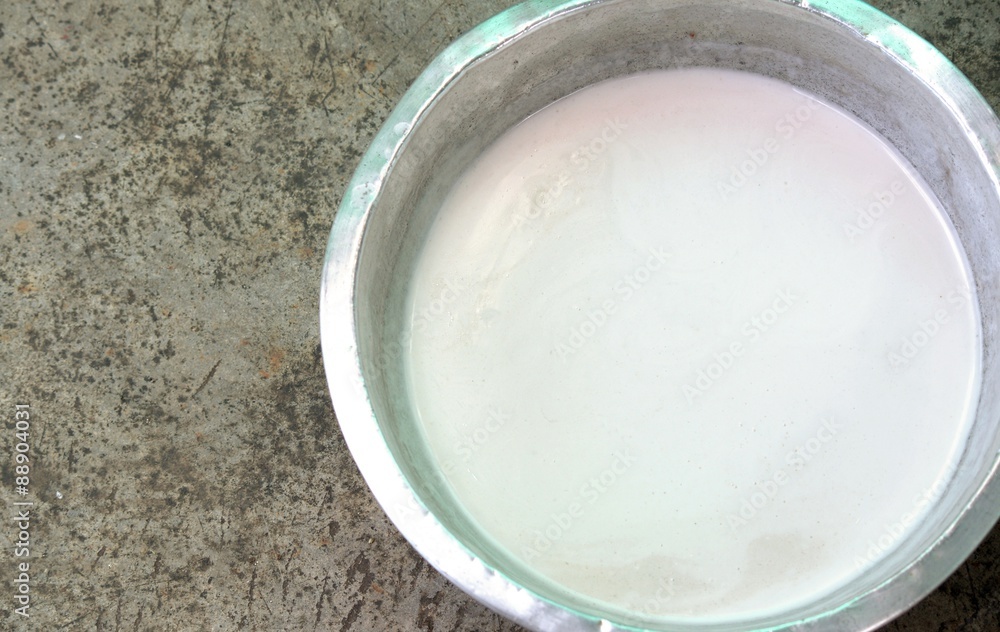 Coconut milk in a stainless steel bowl on cement background. Coconut milk in a stainless steel bowl on cement background.