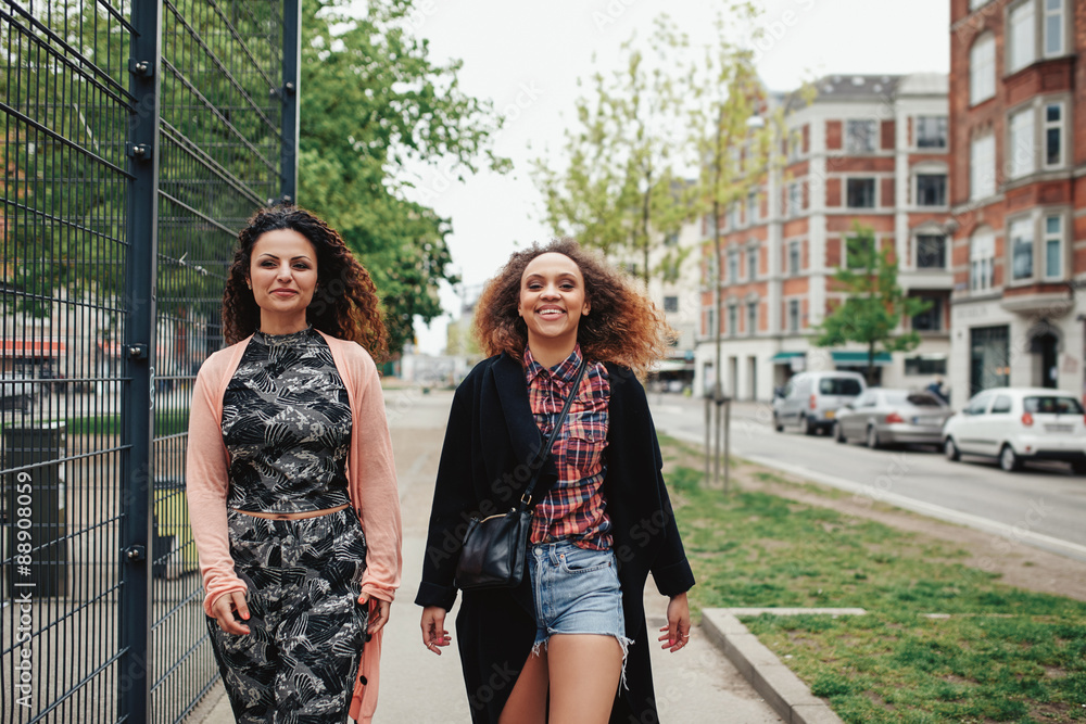 Two girlfriends walking along city street Two girlfriends walking along city street